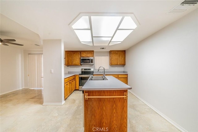 kitchen with appliances with stainless steel finishes, ceiling fan, a kitchen island with sink, and sink