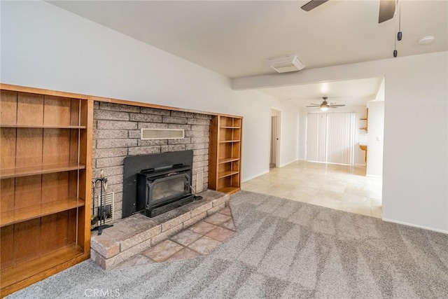 carpeted living room with a wood stove and ceiling fan