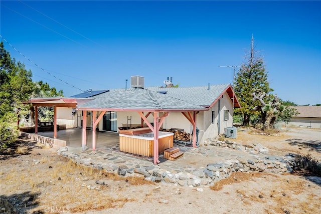 rear view of property with a hot tub, a patio, and central AC unit