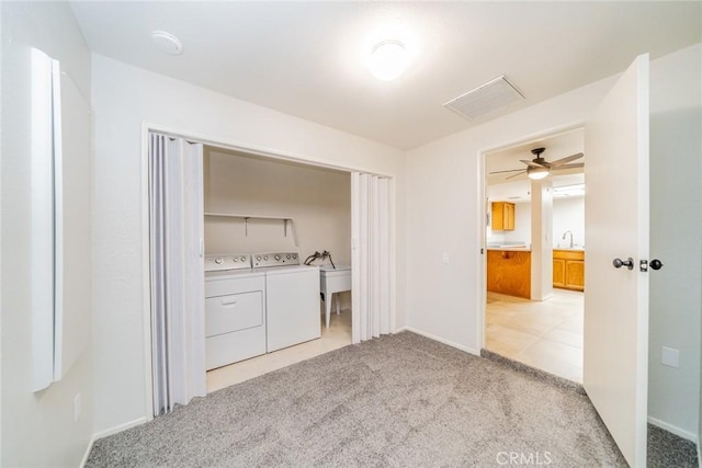 interior space featuring washing machine and clothes dryer, light carpet, sink, and ceiling fan