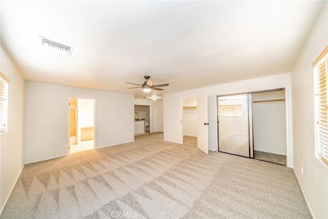 interior space featuring multiple windows, ensuite bathroom, ceiling fan, and light colored carpet