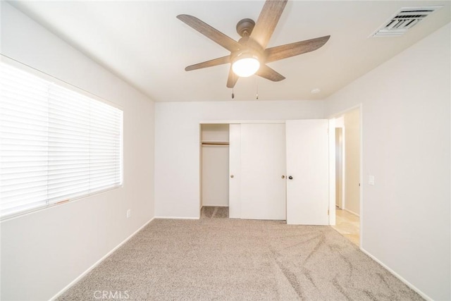 unfurnished bedroom with a closet, light colored carpet, and ceiling fan