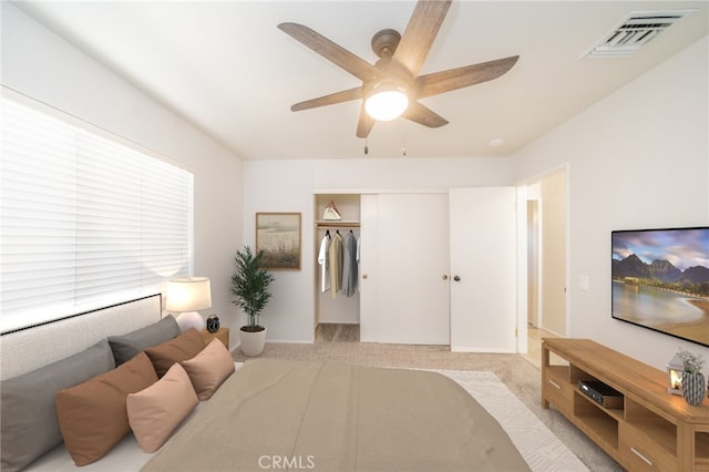 bedroom with ceiling fan, light colored carpet, multiple windows, and a closet