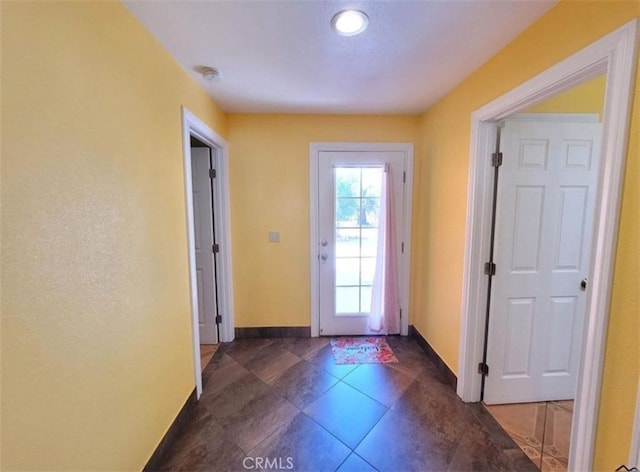 doorway with dark tile patterned floors