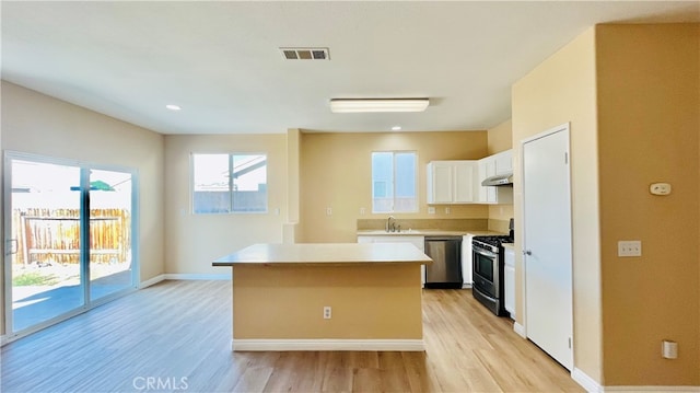 kitchen featuring sink, a kitchen island, light hardwood / wood-style flooring, white cabinetry, and appliances with stainless steel finishes