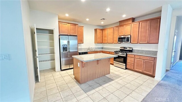 kitchen featuring light tile patterned floors, a breakfast bar area, stainless steel appliances, a center island, and light stone countertops