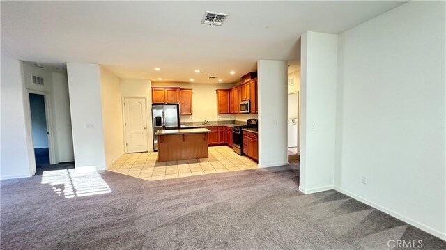 kitchen featuring sink, a breakfast bar area, appliances with stainless steel finishes, a kitchen island, and light carpet