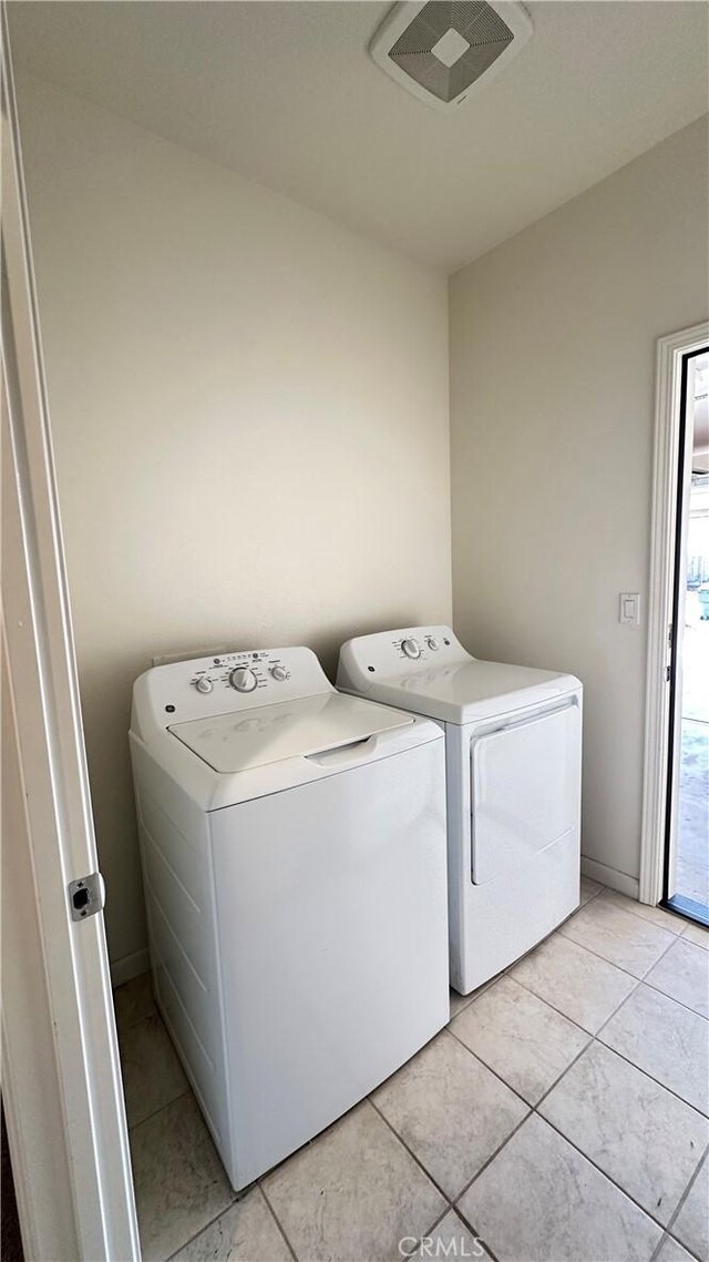 clothes washing area with separate washer and dryer and light tile patterned floors