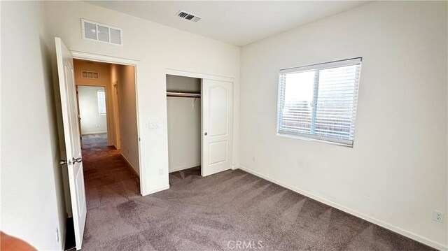 unfurnished bedroom featuring a closet and dark colored carpet