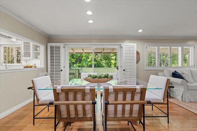 dining area with sink, crown molding, and light wood-type flooring