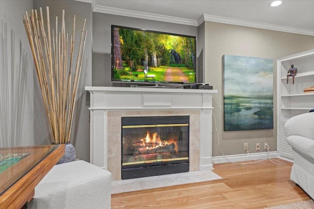 sitting room featuring a tiled fireplace, wood-type flooring, and ornamental molding