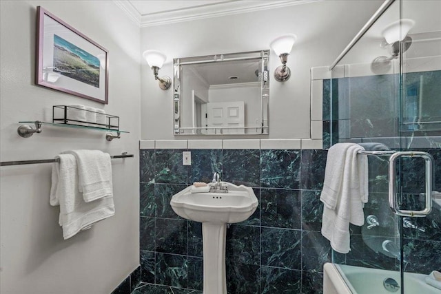 bathroom featuring crown molding, combined bath / shower with glass door, and tile walls