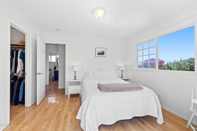 bedroom with a spacious closet, light hardwood / wood-style flooring, and a closet