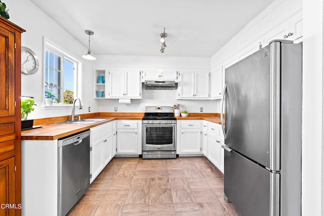 kitchen featuring appliances with stainless steel finishes, hanging light fixtures, white cabinets, butcher block counters, and sink