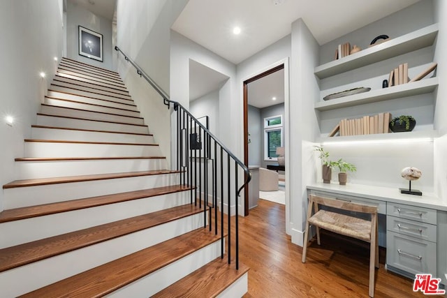 staircase with built in desk and hardwood / wood-style floors