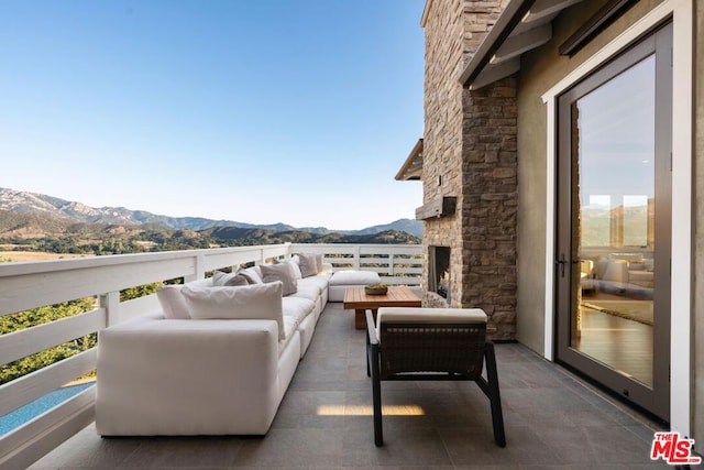 view of patio featuring a balcony, an outdoor living space, and a mountain view