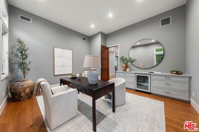 home office featuring light hardwood / wood-style flooring and wine cooler