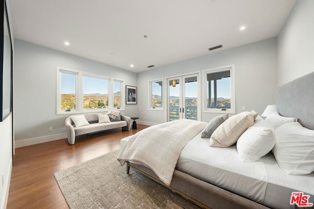 bedroom featuring french doors, a mountain view, hardwood / wood-style flooring, and access to exterior