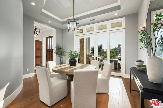 dining room with wood-type flooring, a tray ceiling, and a chandelier