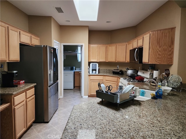 kitchen featuring stainless steel refrigerator with ice dispenser, washer / clothes dryer, light brown cabinets, and white gas range