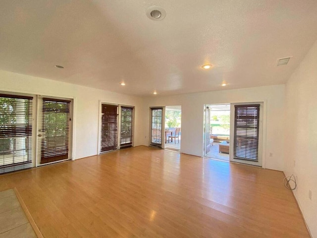 spare room with a textured ceiling and light hardwood / wood-style floors