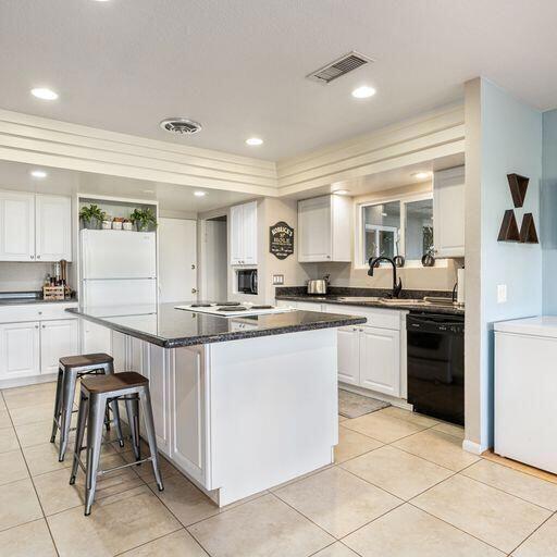 kitchen featuring dishwasher, white cabinetry, white fridge, and a center island