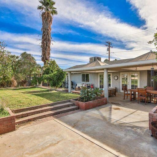 back of property with a lawn and a patio area