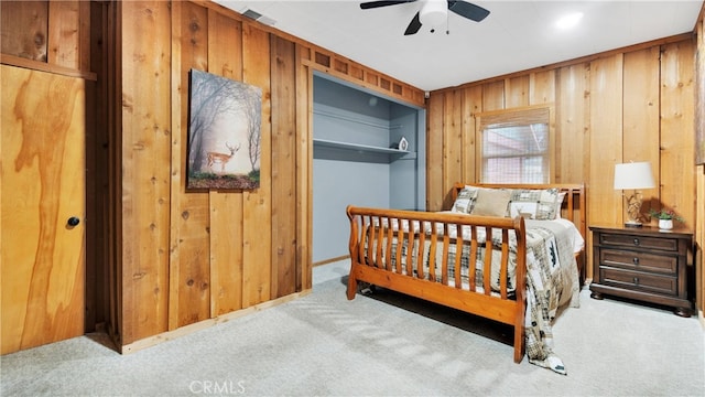 bedroom featuring wood walls, ceiling fan, and light colored carpet