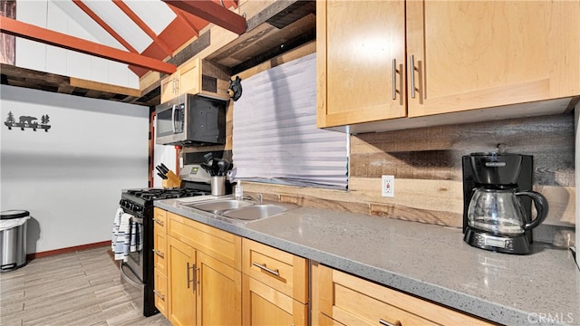 kitchen featuring light stone counters, light brown cabinets, sink, black range with gas stovetop, and light hardwood / wood-style floors