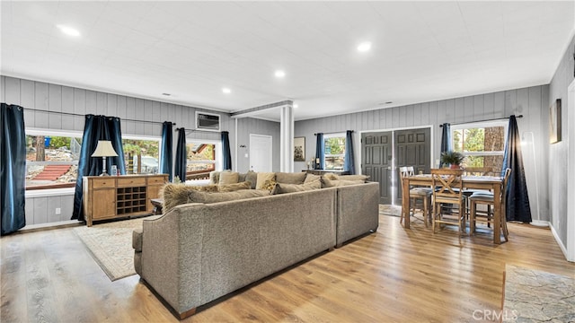 living room with wooden walls, light hardwood / wood-style flooring, and plenty of natural light