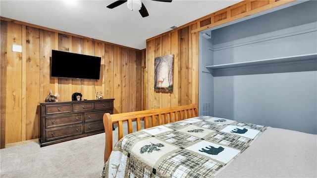 carpeted bedroom featuring ceiling fan and wood walls