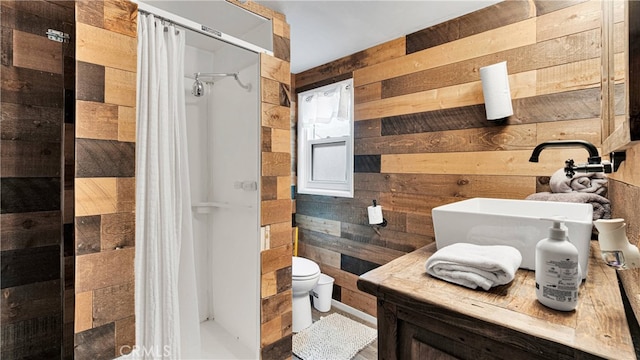 bathroom featuring wood walls, toilet, a shower with shower curtain, and sink