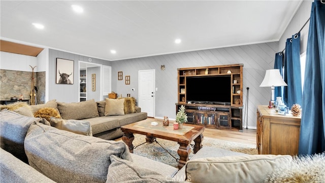 living room featuring crown molding, light hardwood / wood-style floors, and wood walls