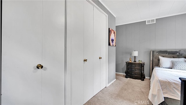 bedroom with crown molding, wooden walls, and light carpet