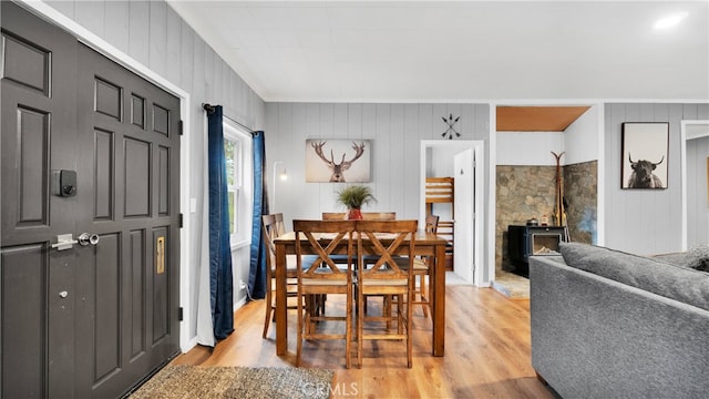 dining space with light wood-type flooring and wood walls