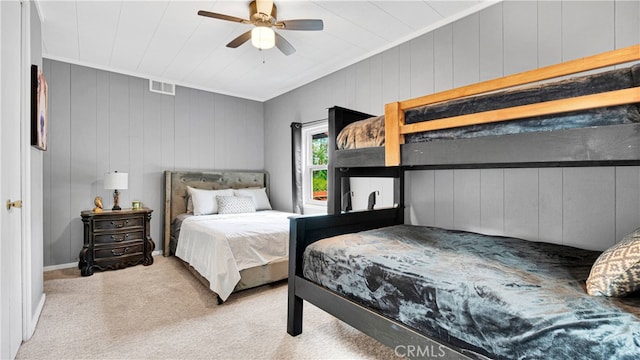 bedroom with wooden walls, ceiling fan, and light colored carpet