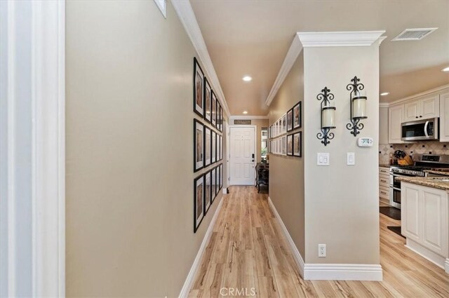 hall featuring ornamental molding and light hardwood / wood-style flooring