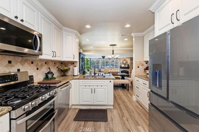 kitchen with white cabinetry, stainless steel appliances, kitchen peninsula, and hanging light fixtures