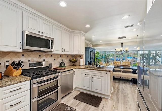 kitchen featuring appliances with stainless steel finishes, pendant lighting, white cabinets, and kitchen peninsula