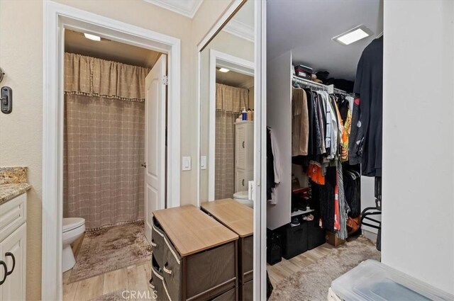 bathroom featuring hardwood / wood-style flooring, vanity, ornamental molding, a shower with curtain, and toilet