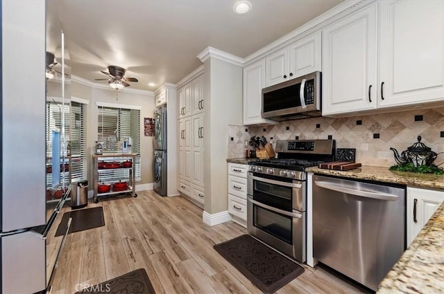 kitchen with ornamental molding, stainless steel appliances, light stone countertops, light hardwood / wood-style floors, and white cabinets