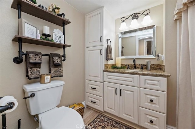 bathroom with vanity, toilet, and hardwood / wood-style floors