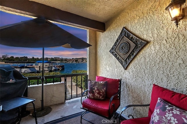 balcony at dusk featuring a water view