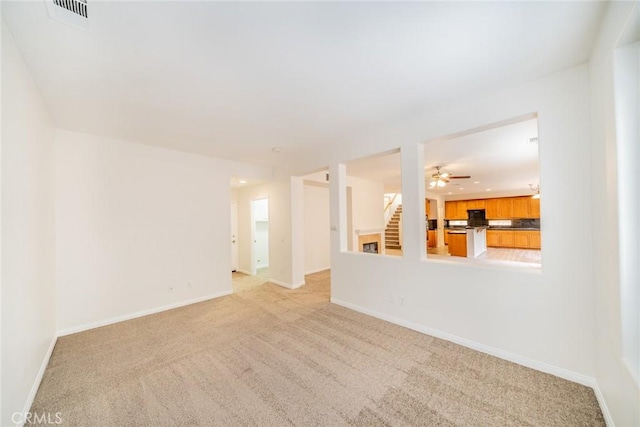 empty room featuring light carpet, visible vents, baseboards, stairway, and recessed lighting