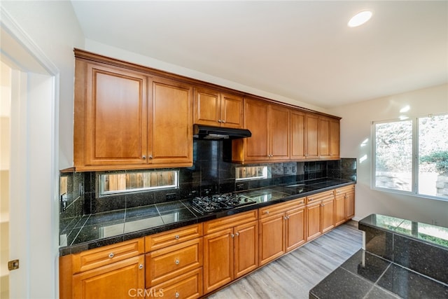 kitchen with decorative backsplash, black gas stovetop, and light wood-type flooring