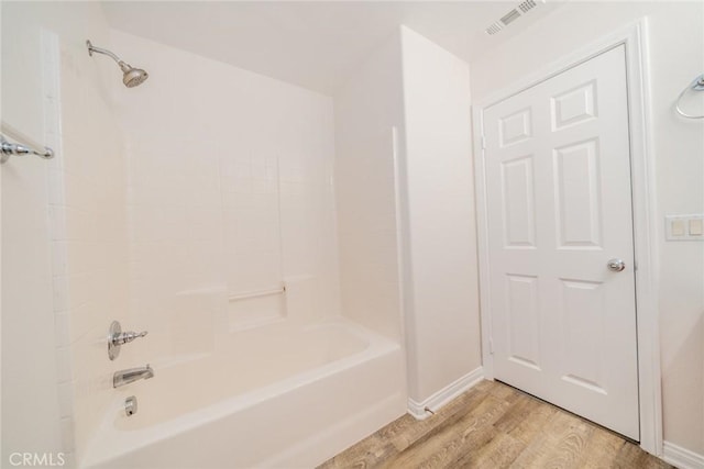 bathroom featuring baseboards, visible vents, wood finished floors, and shower / bathing tub combination