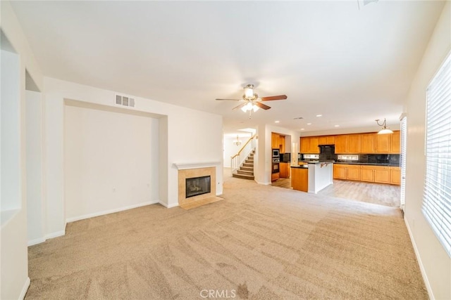 unfurnished living room with recessed lighting, a fireplace with flush hearth, visible vents, baseboards, and stairway