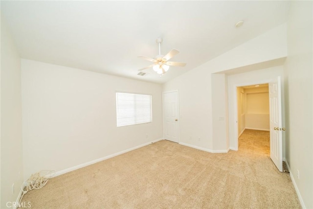 empty room with baseboards, visible vents, a ceiling fan, light colored carpet, and vaulted ceiling