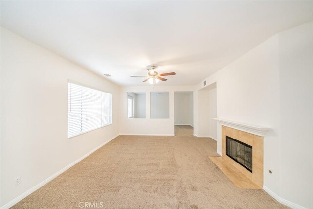 unfurnished living room featuring ceiling fan, a fireplace, and light colored carpet