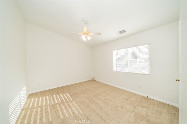 carpeted spare room featuring ceiling fan, visible vents, and baseboards